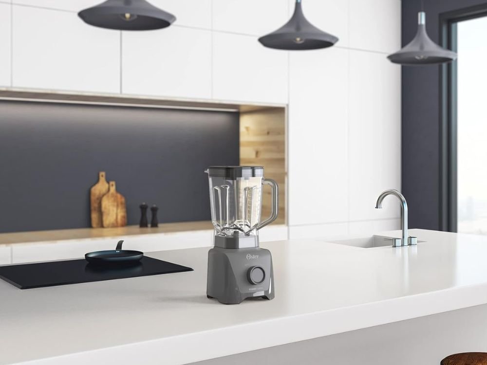 Liquidificador Oster 1100 Full 3,2L na cor cinza, com design moderno e jarra grande de alta capacidade, ideal para preparar sucos, vitaminas, sopas e receitas variadas, destacando sua potência de 1100W, controle de velocidades e uso prático no dia a dia da cozinha.